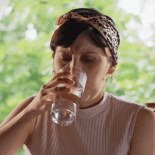 a woman wearing a leopard print headband is drinking from a glass