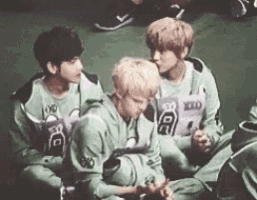 a group of young men are sitting on the ground and talking to each other .