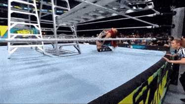 a woman is kneeling down in a wrestling ring while a referee watches