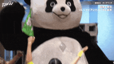 a stuffed panda bear is being held up by a person with the letters tjpw on the bottom right