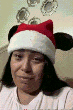 a woman wearing a santa hat with mickey mouse ears on it
