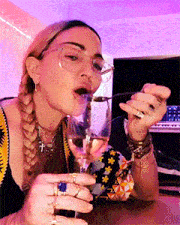 a woman wearing glasses is drinking from a glass