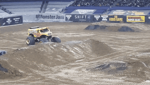 a monster truck is driving down a dirt track in front of a wall that says monster jam