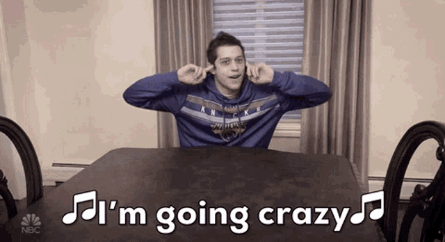 a man is sitting at a table with his hands in his ears and the words i 'm going crazy