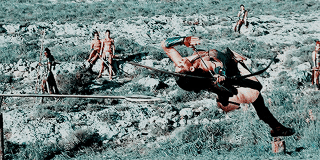 a man with a bow and arrow is laying on the ground .