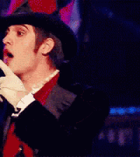 a man wearing a top hat and gloves holds his finger to his mouth