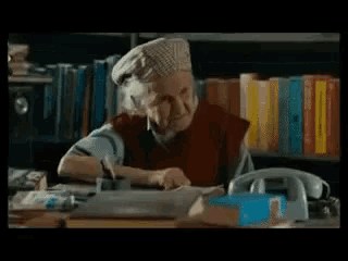 a person sitting at a desk in front of a bookshelf with books on it