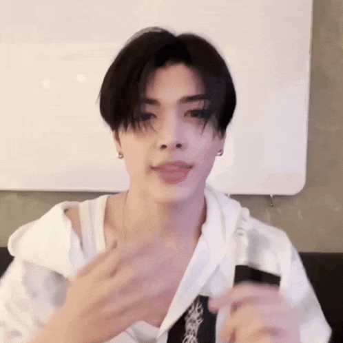 a young man with black hair is wearing a white tank top and earrings .
