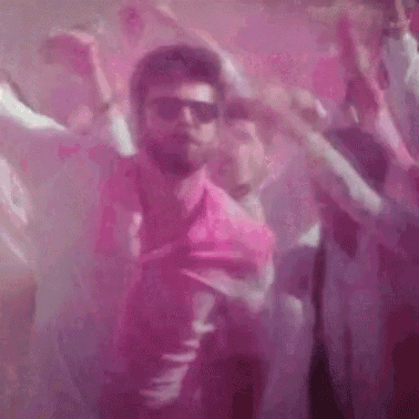 a group of people are dancing in a room with pink powder in the background .