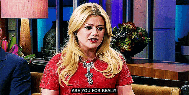 a blonde woman in a red dress is asking are you for real