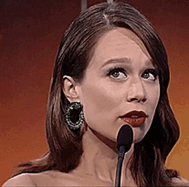 a woman speaking into a microphone wearing earrings