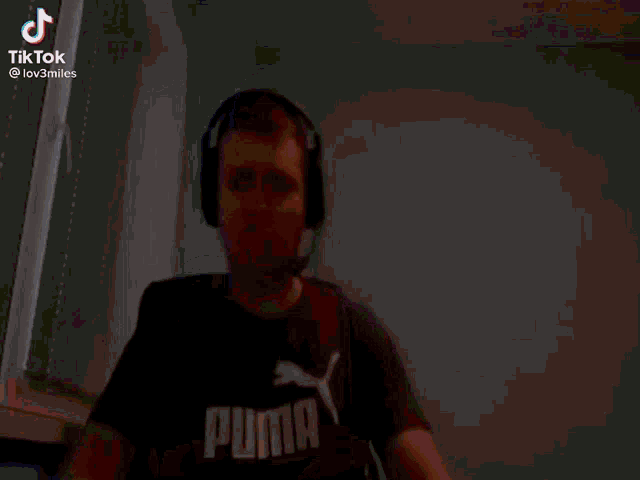 a man wearing headphones and a puma shirt is dancing in a room .