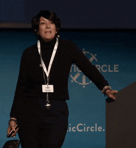 a woman stands in front of a blue wall that says circle