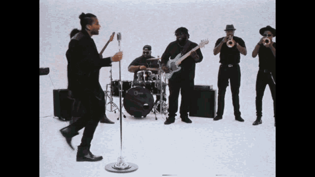 a man singing into a microphone in front of a group of musicians