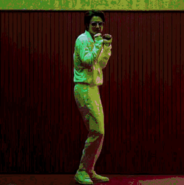 a man in white pants is standing in front of a pink wall .