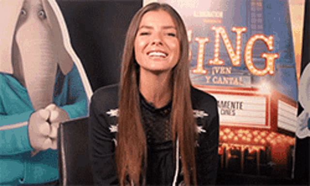 a woman is smiling in front of a sign that says " ing "