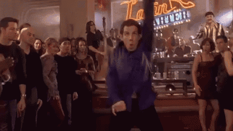 a man in a blue shirt is dancing in front of a crowd of people in a club .