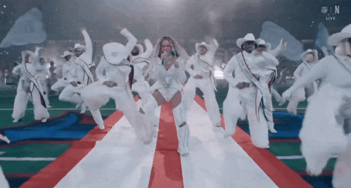 a group of people are dancing on a red white and blue striped carpet with the nfl logo in the background