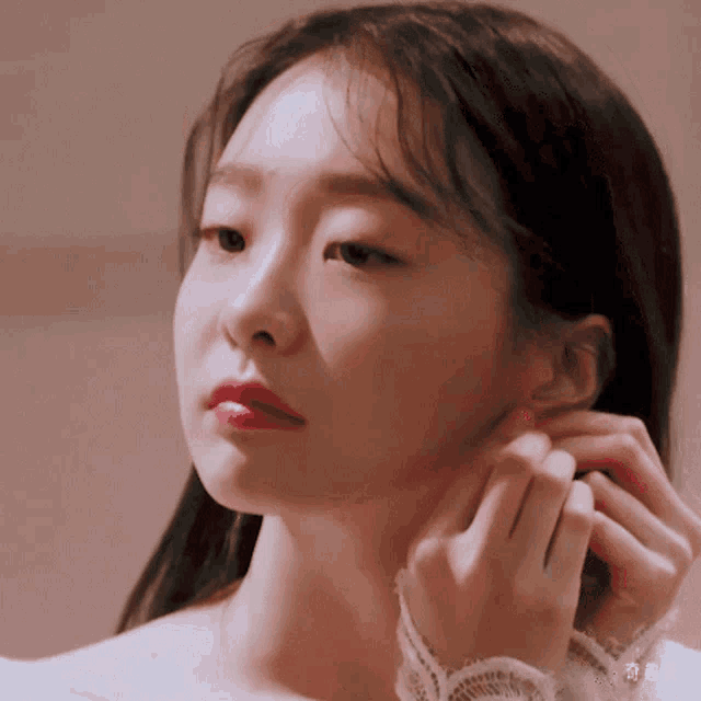 a close up of a woman adjusting her earring with chinese writing on the bottom right