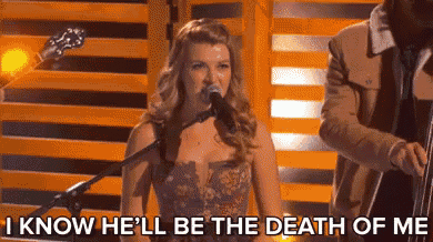 a woman singing into a microphone with the words `` i know he 'll be the death of me '' behind her .