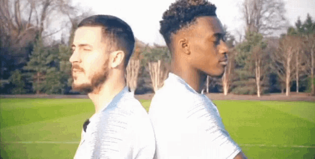 two men are standing back to back on a field