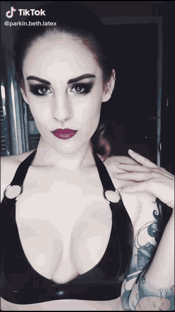 a woman with a tattoo on her arm is wearing a black bra and a tiktok watermark