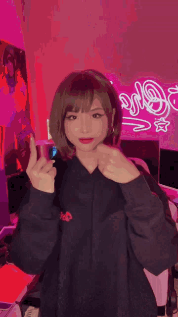 a girl in a black hoodie is giving a thumbs up