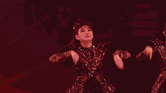 a woman in a black and gold outfit is dancing on a stage