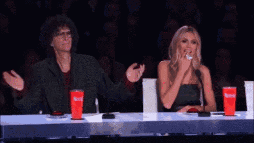 a man and a woman are sitting at a table with red cups that say coca cola on them .
