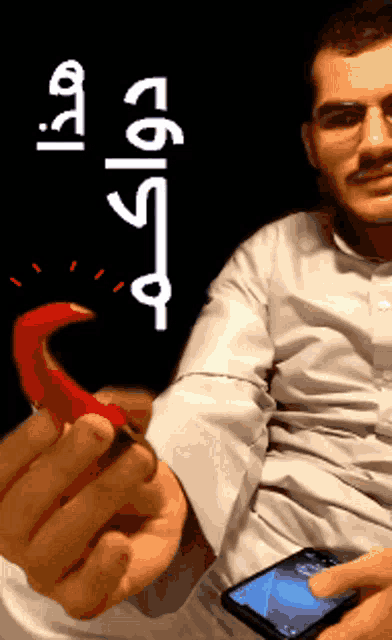 a man in a white shirt is holding a red pepper in his right hand