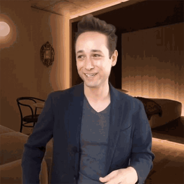 a man wearing a blue jacket and a grey shirt is smiling