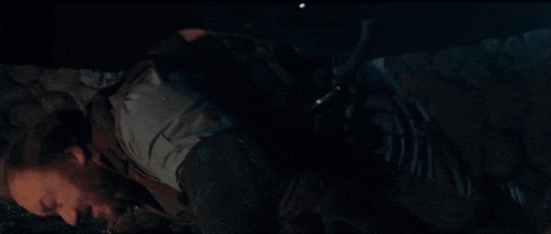 a man is laying on the ground in a dark room with a backpack on his back .