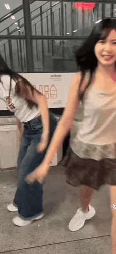 two girls are dancing in front of a sign that says recycling