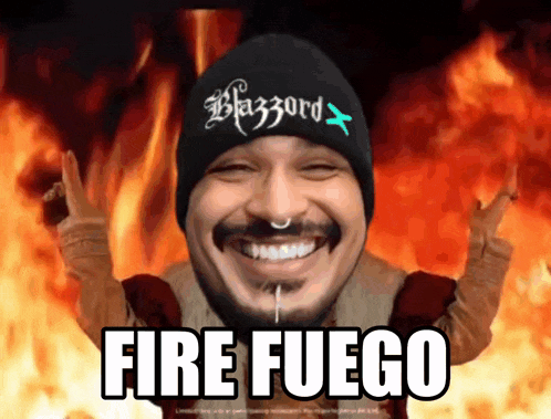 a man wearing a beanie that says blazzard on it is smiling in front of a fire background