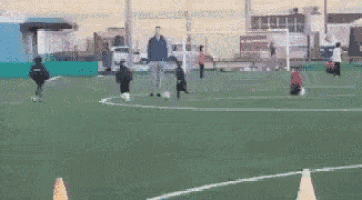 a group of children are playing soccer on a field with a cone in the middle of the field .