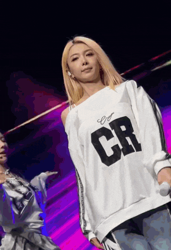 a woman with blonde hair is wearing a white shirt with cr on it