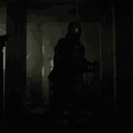 a silhouette of a person standing in a dark room holding a gun .