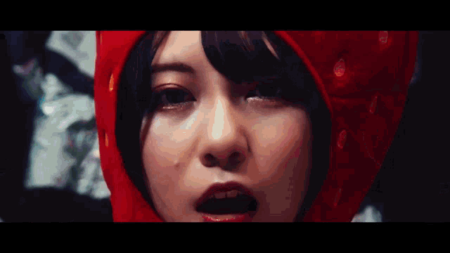 a woman wearing a strawberry hat is surrounded by other people