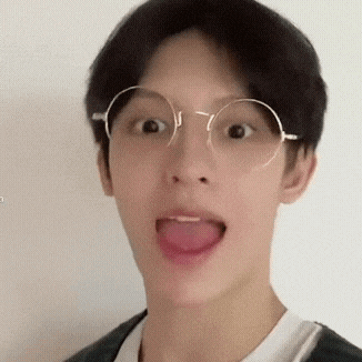 a young man with glasses is sticking his tongue out .