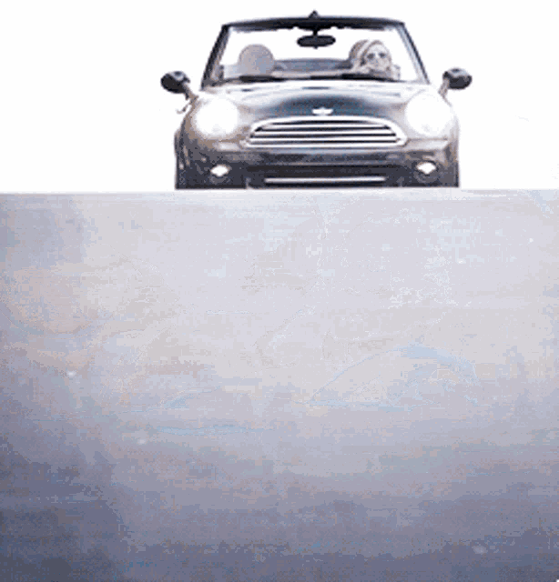 a woman is driving a convertible mini cooper
