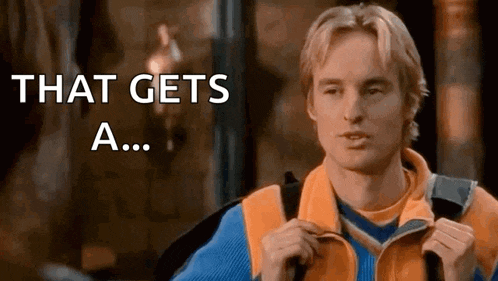 a man in an orange jacket is holding a backpack and saying `` that gets a ... '' .