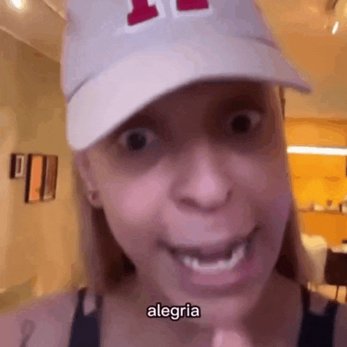 a woman wearing a white hat and smiling with the word alegria written on her face .