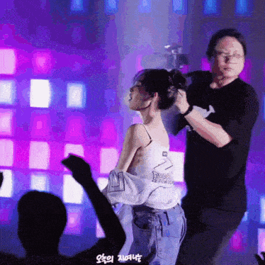 a man is fixing a woman 's hair in front of a crowd of people