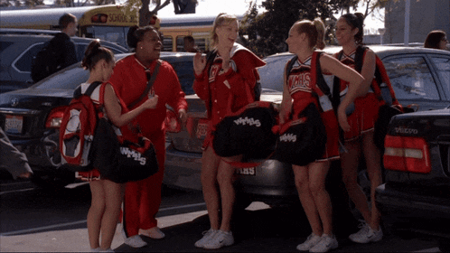 a group of cheerleaders are standing in front of a volvo
