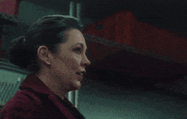 a woman in a red coat is standing next to a chained man