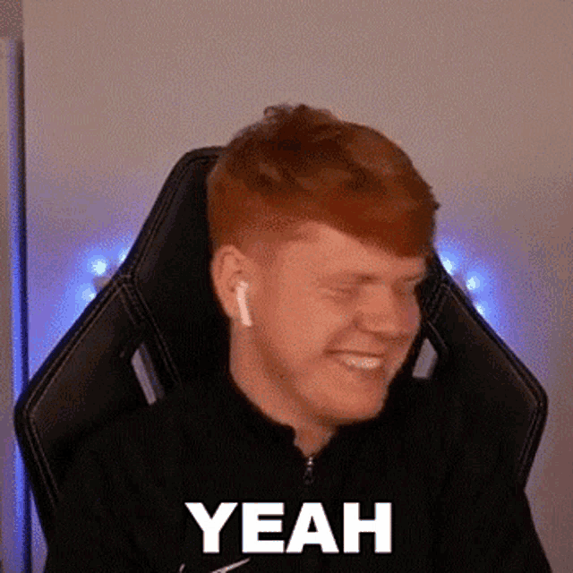 a man with red hair is sitting in a chair with his eyes closed and wearing ear buds .