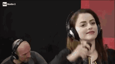 a woman wearing headphones is dancing while a man holds a microphone in front of her .