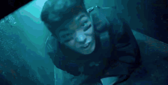 a man is swimming underwater in a pool and looking up at the camera .