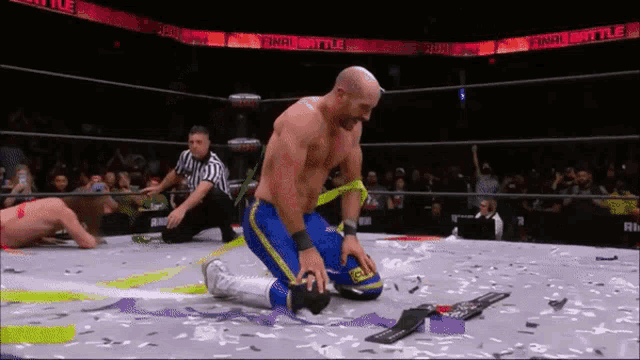 a wrestler is kneeling down in a ring with a referee behind him and a sign that says final battle