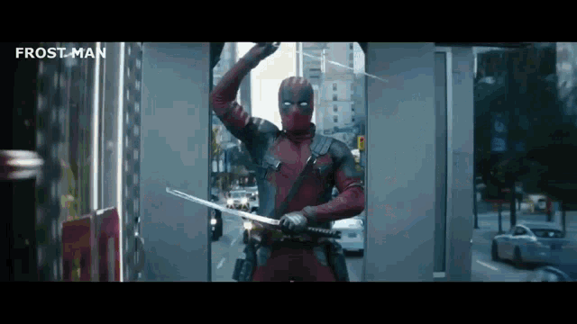 a man in a deadpool costume is holding a sword in front of a building .